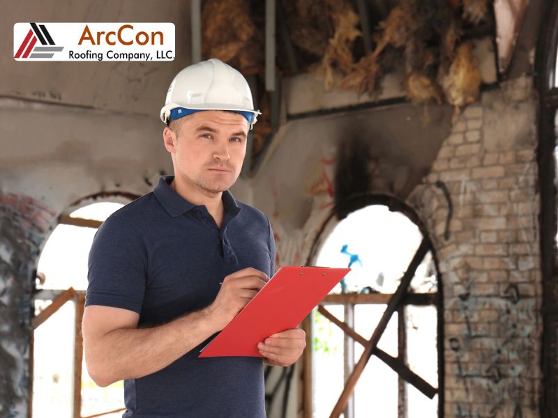 An insurance adjuster with a red clipboard wearing a safety gear